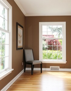 White windows on brown walls with chair in corner